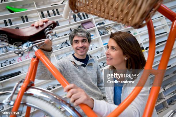 couple at a bicycle store looking at the saddle of a vintage bicycle very happy - argentina leather stock pictures, royalty-free photos & images