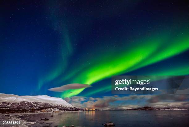 winter: awesome aurora borealis appears over tornetrask lake and mount nuolja in swedish lapland - sweden stock pictures, royalty-free photos & images