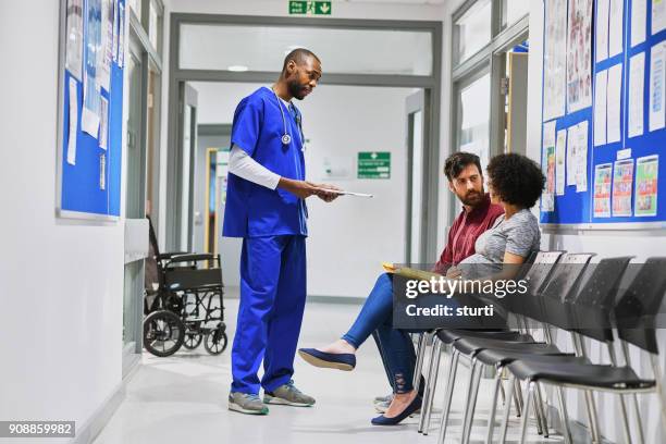 pregnant couple chatting to a doctor - maternity ward stock pictures, royalty-free photos & images
