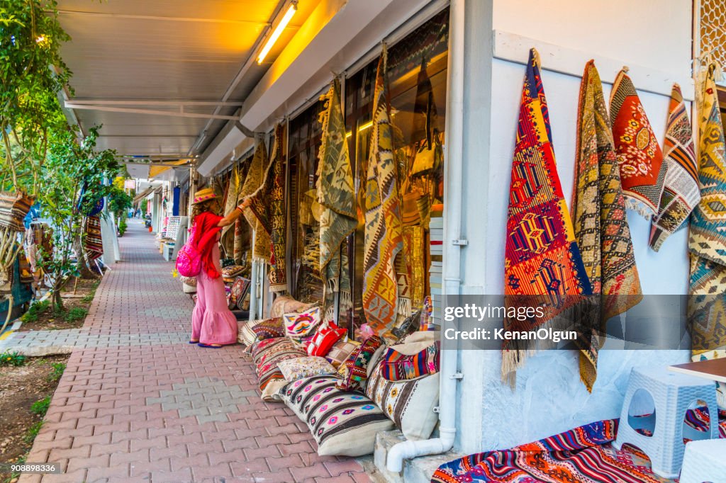 Woman tourist is looking at the carpets in the carpet shop. Datca, Mugla / Turkey.