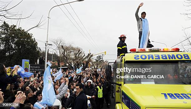 The newly-crowned US Open champion Juan Martin Del Potro waves at people gathered to see him from a fire engine on September 17 following his arrival...