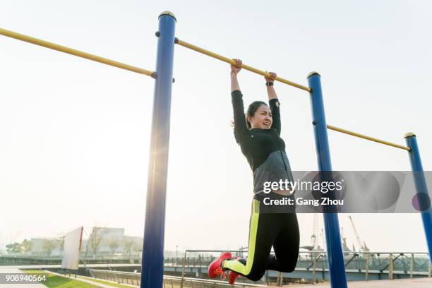 young woman hanging on horizontal bar - horizontal bars stock pictures, royalty-free photos & images