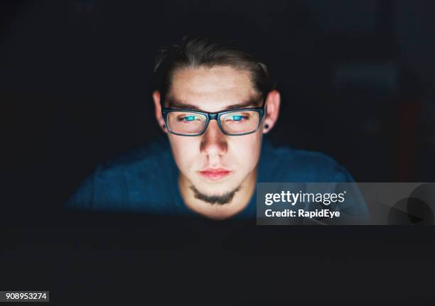 young man stares intently at computer monitor at night - teenager staring imagens e fotografias de stock