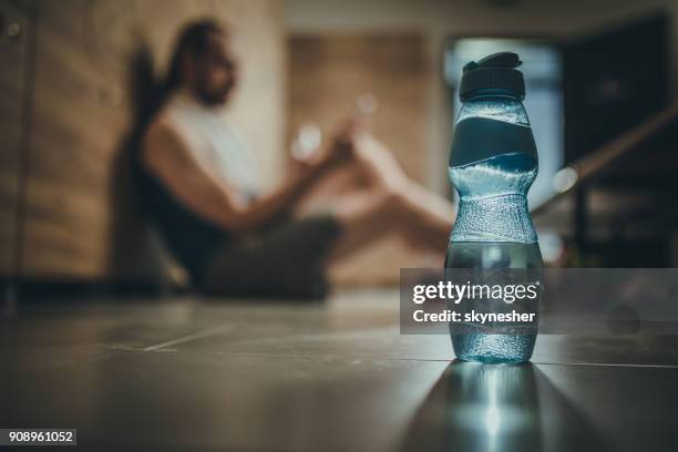 close up of water bottle in locker room with an athlete in the background. - locker room stock pictures, royalty-free photos & images