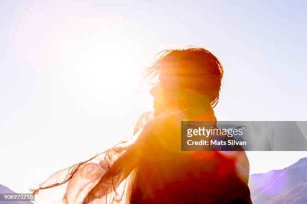 woman with moving hair and scarf in sunlight in a windy day - sovraesposizione effetti fotografici foto e immagini stock