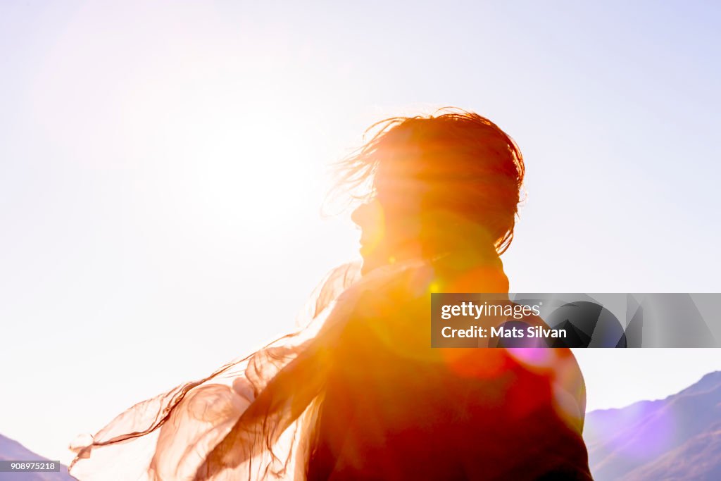 Woman with Moving Hair and Scarf in Sunlight in a Windy Day