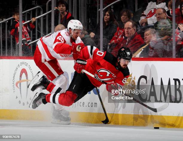 Marcus Johansson of the New Jersey Devils is hit by Danny DeKeyser of the Detroit Red Wings in the third period on January 22, 2018 at Prudential...