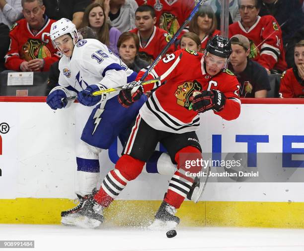 Michael Bournival of the Tampa Bay Lightning and Jonathan Toews of the Chicago Blackhawks battle for the puck along the boards at the United Center...