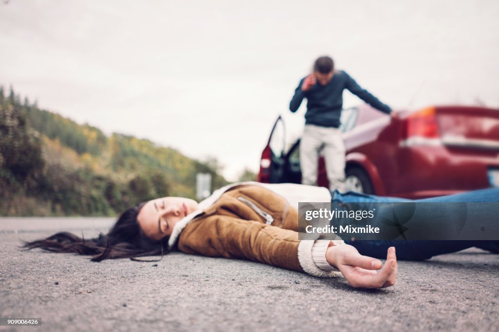 Brünette Frau im Vordergrund, die bewusstlos auf der Straße liegen.