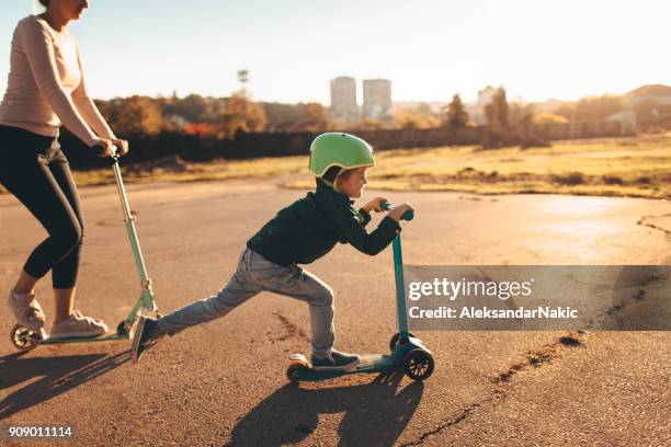 bambino in sella a uno scooter push con sua madre - monopattino foto e immagini stock