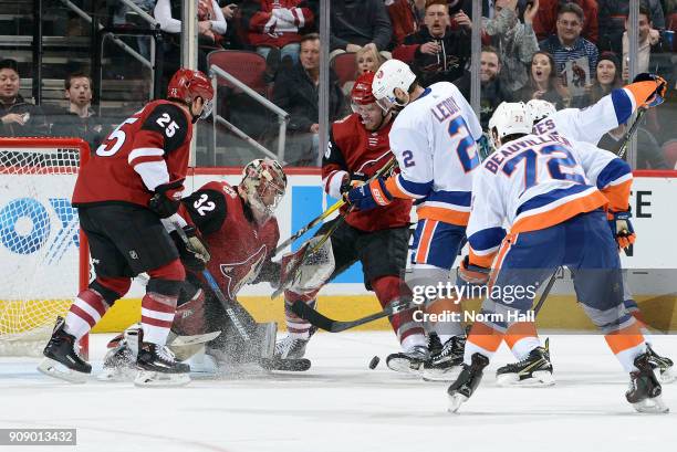 Goalie Antti Raanta of the Arizona Coyotes looks for the puck in a crowd as Christian Fischer of the Coyotes and Nick Leddy of the New York Islanders...