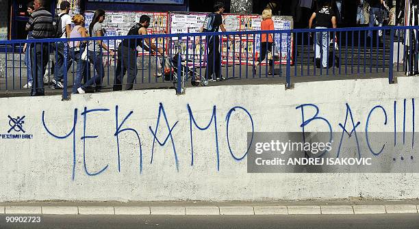 Aleksandra Niksic - People walk past graffiti reading "We are expecting you" referring to the upcoming gay pride parade in Belgrade on September 15,...