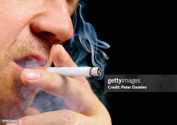 senior male smoking cigarette on black background - humo fotografías e imágenes de stock