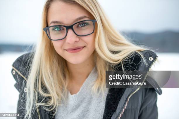ritratto di una bella ragazza adolescente sorridente che guarda la macchina fotografica all'aperto sulla neve - blonde glasses foto e immagini stock