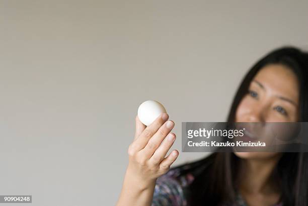 young woman looking at  an egg - kazuko kimizuka ストックフォトと画像