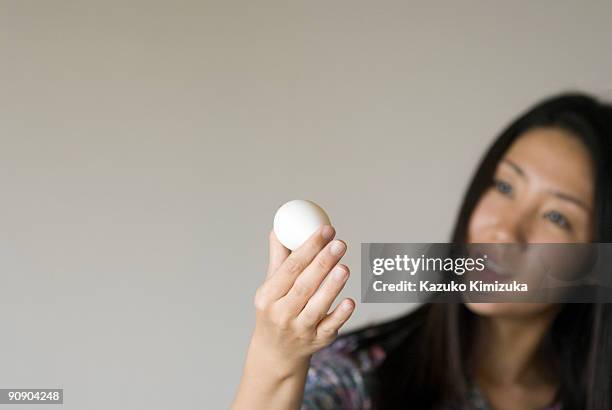 young woman looking at  an egg - kazuko kimizuka 個照片及圖片檔