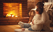family mother and child hugs and warm on winter evening by fireplace