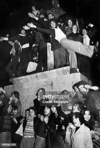 New Year revellers besiege the statue of Lady Godiva during the celebrations to see in 1977, 1st January 1977.