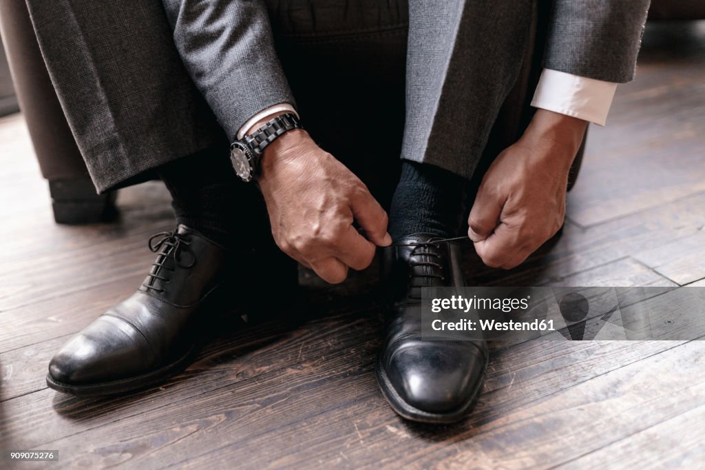 Businessman putting on shoes, tying shoelace