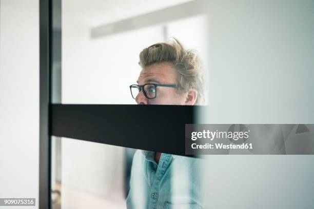wide-eyed businessman behind glass pane in office - posteriore foto e immagini stock