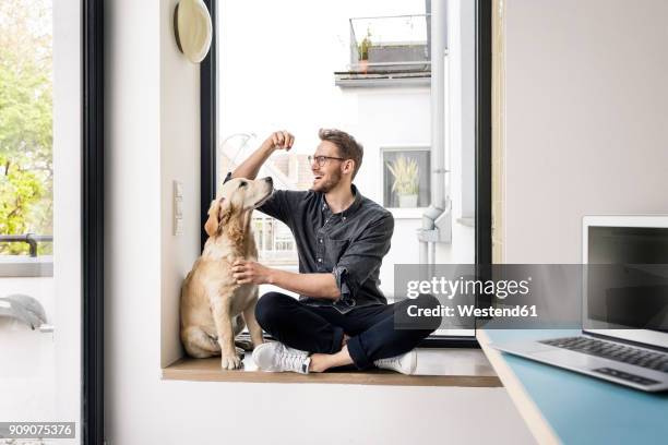 happy man with dog sitting at the window - man and dog stock pictures, royalty-free photos & images