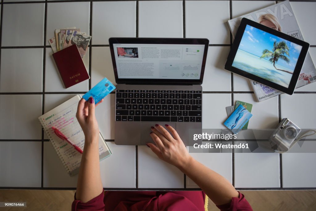 Young woman using laptop, paying with credit card, travel booking