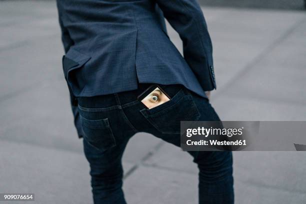 businessman with cell phone with image of eyes in his trouser pocket - casual clothing photos stock-fotos und bilder