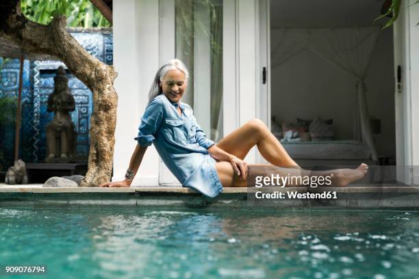 beautiful senior woman relaxing at pool in front of her house - comfortable retirement stock pictures, royalty-free photos & images