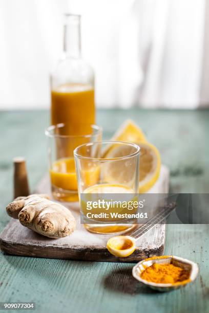 detox drink, ginger, lemon and orange juice with curcuma and chilli powder - ginger glasses stock-fotos und bilder
