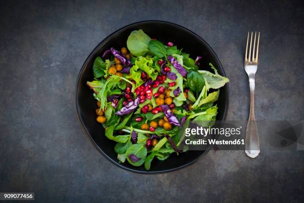 bowl of mixed leaf salad with pomegranate seed, red cabbage and roasted curcuma chick peas - chick pea salad stock pictures, royalty-free photos & images
