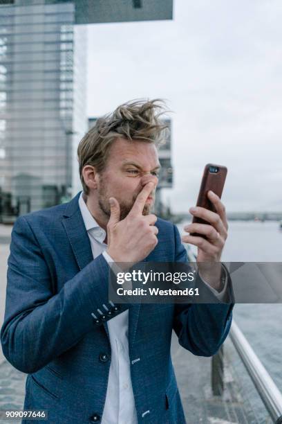 businessman with cell phone picking nose - 40's rumpled business man stockfoto's en -beelden