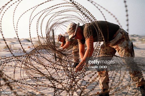 Marines deploy concertina wire to prevent infiltration of their encampment during Operation Desert Shield.