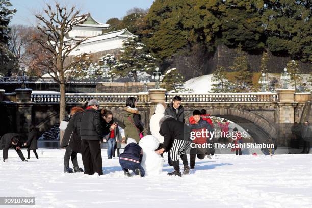 Foreign tourists make the most of the wintry surprise by making snowmen in front of Nijubashi bridge in the grounds of the Imperial Place on January...