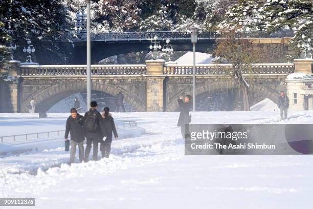 People walk at snow covered Nijubashi Bridge of the Imperial Palace on January 23, 2018 in Tokyo, Japan. The snowstorm affected traffic and public...