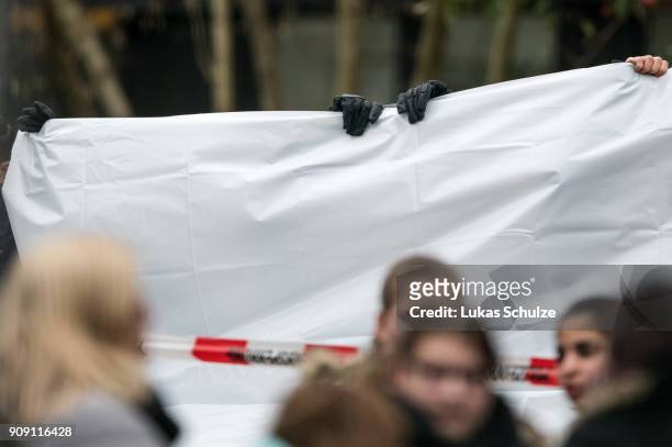 Police guards use tarpaulin to block the view as a body of a teenager is placed into a hearse at the Kaethe Kollwitz comprehensive school following...
