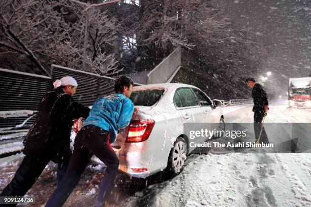 People push a car stranded on a snow-covered road on January 22, 2018 in Tokyo, Japan. The Japan Meteorological Agency is forecasting 20 cm of snow...