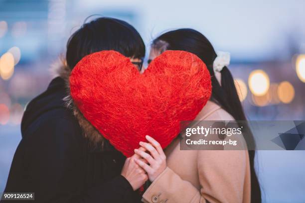 couple hiding behing heart shape and kissing each other - valentine japan stock pictures, royalty-free photos & images