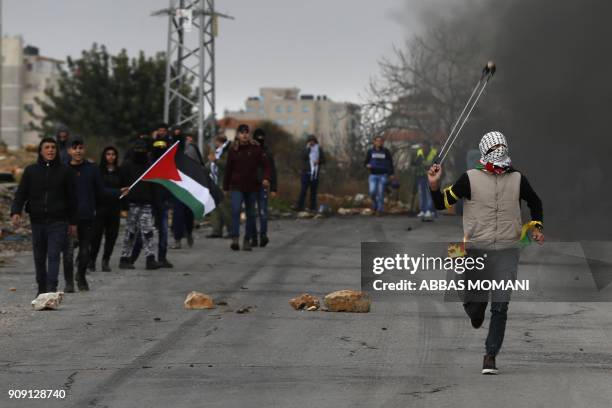 Palestinian protester throws a stone towards Israeli forces during clashes near the Jewish settlement of Beit El, on the outskirts of the West Bank...