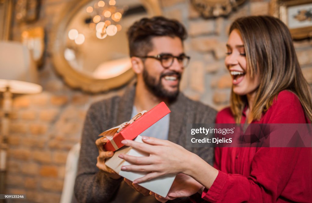 Cheerful young woman receiving a gift from her boyfriend.