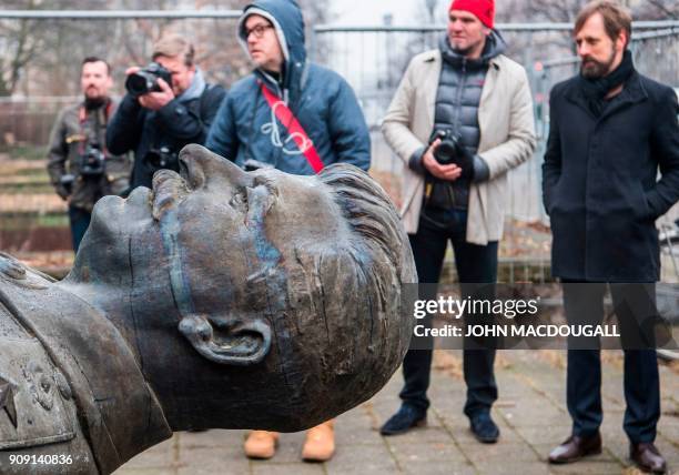 Reporters look on as a 4,8-metre-high statue of former Soviet dictator Joseph Stalin is lifted by a crane on Berlin's Karl-Marx Allee on January 23,...
