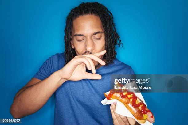 young urban man eating hotdog - indulgence foto e immagini stock