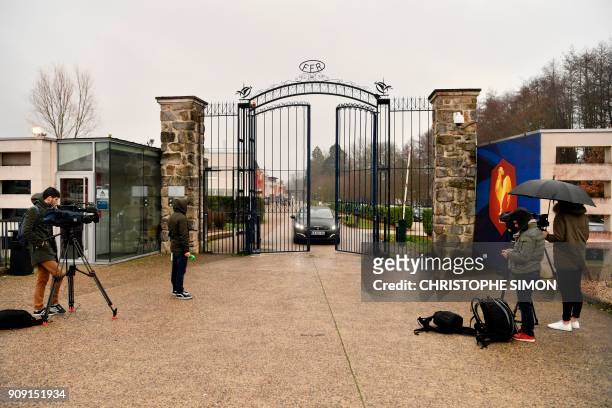 Reporters broadcast from the front entrance of the headquarters of the French Rugby Federation while a car drives through the gates on January 23,...