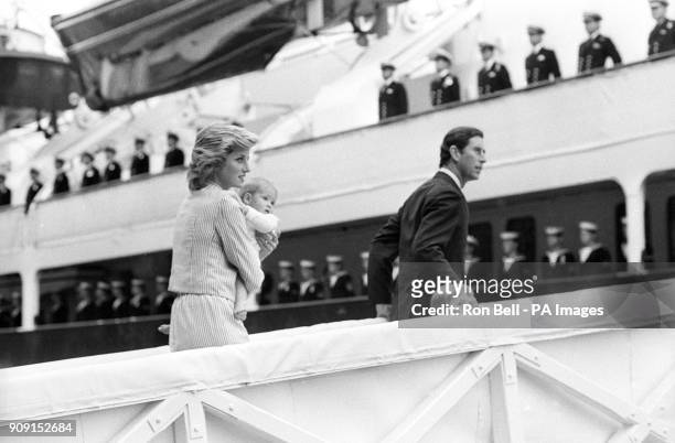 Prince Charles holds Prince William's hand while the Princess of Wales carries Prince Harry up the gangway to board the Royal Yacht Britannia at...