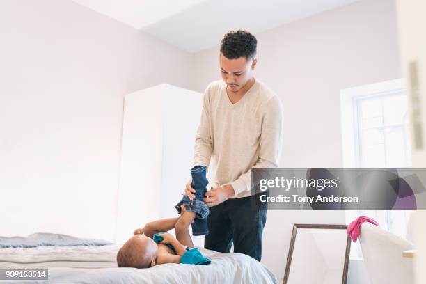 Young father changing infant daughter's diaper at home