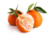One half peeled and two whole mandarins with leaves isolated on white.