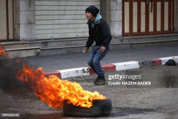 Palestinian protester looks on ahead of throwing a stone towards Israeli forces during clashes in the city of Hebron in the occupied West Bank, on...