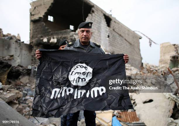 Police officer shows the Islamic State flag picked up in the old town on January 14, 2018 in Mosul, Iraq.