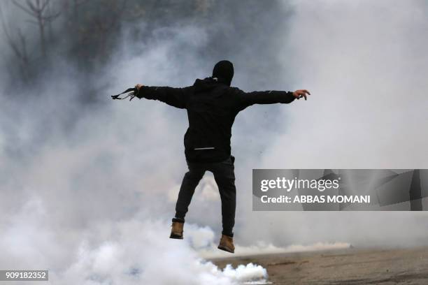 Palestinian protester jumps for cover from tear gas canisters fired by Israeli forces during clashes near the Jewish settlement of Beit El, on the...