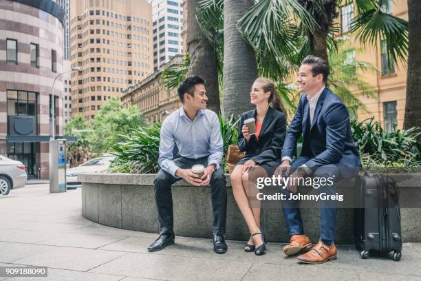 businessmen and woman sitting on wall and talking to young man - sydney cup stock pictures, royalty-free photos & images