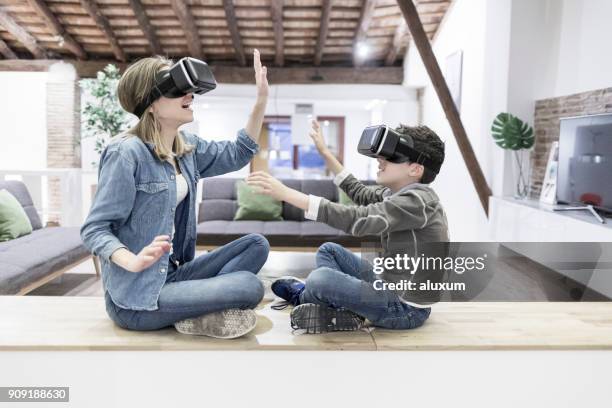 madre e figlio che giocano con gli occhiali della realtà virtuale in salotto - famiglia multimediale foto e immagini stock